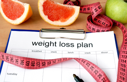 A clipboard with weight loss plan and grapefruit.